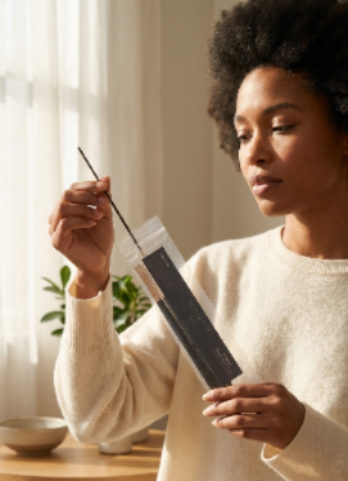 Woman holding a incense in a home setting